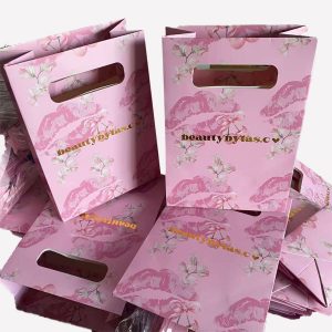 Pink custom die-cut handle paper bag with glossy lamination and gold foil logo